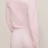 Person wearing a light pink shirt and pants on a plain background