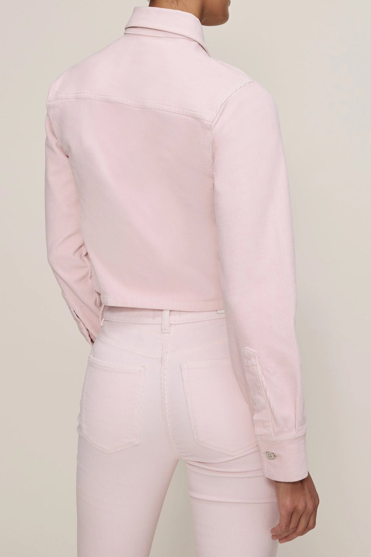 Person wearing a light pink shirt and pants on a plain background