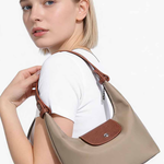 Woman holding a beige handbag with a brown strap on a white background