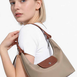 Woman holding a beige handbag with a brown strap on a white background