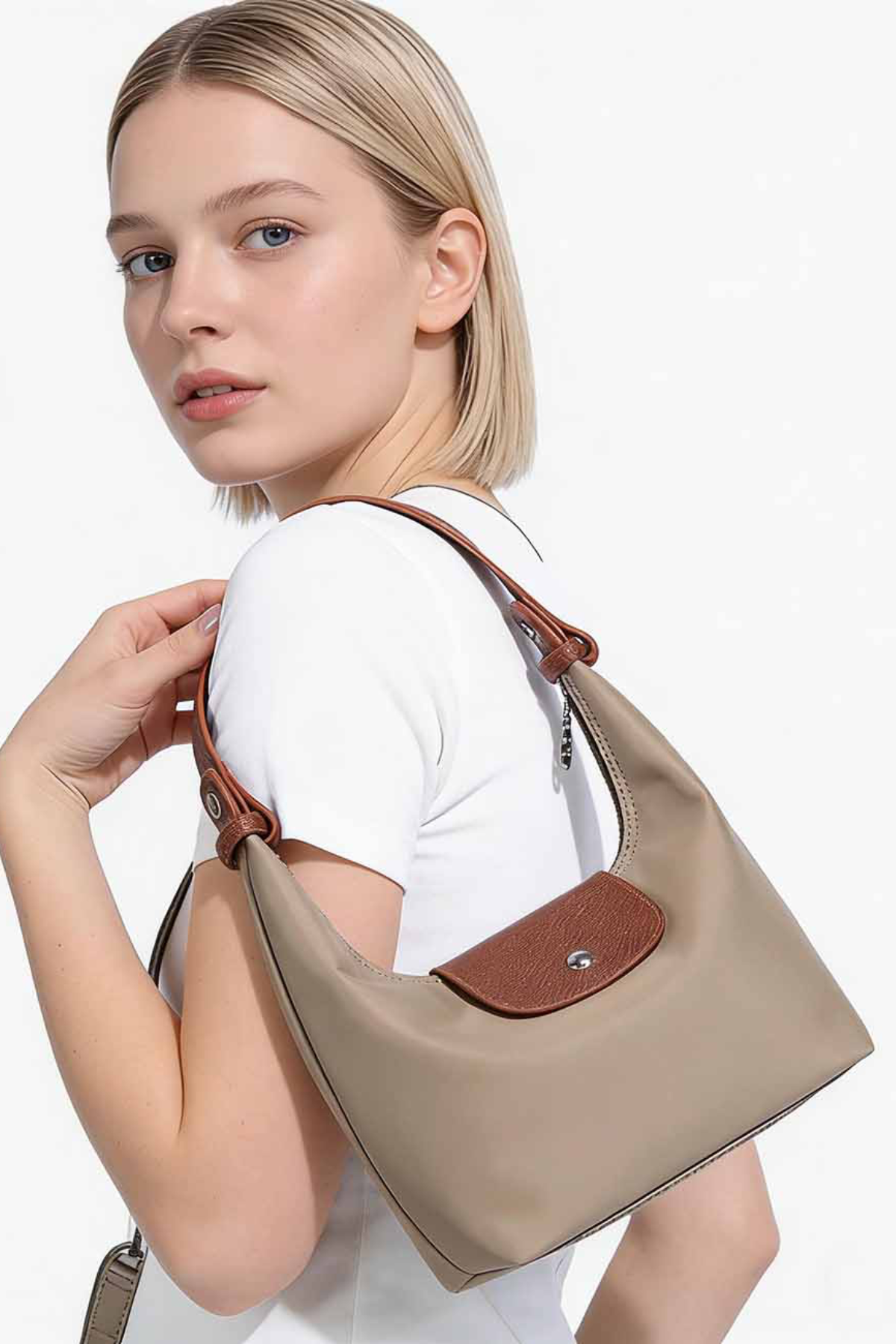 Woman holding a beige handbag with a brown strap on a white background