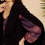 Woman wearing a black coat with purple sleeves against a beige background