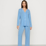 Woman wearing a light blue pajama set against a white background