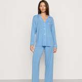 Woman wearing a light blue pajama set against a white background
