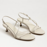 Pair of white high-heeled sandals on a light gray background