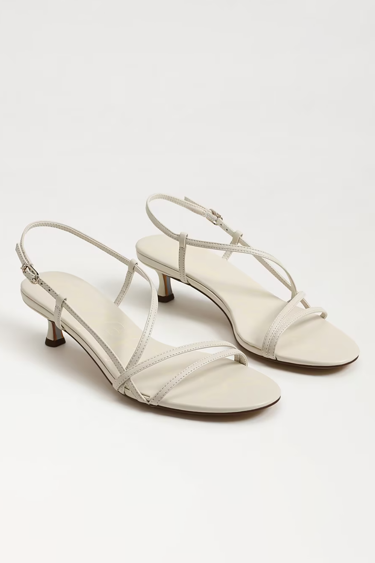 Pair of white high-heeled sandals on a light gray background