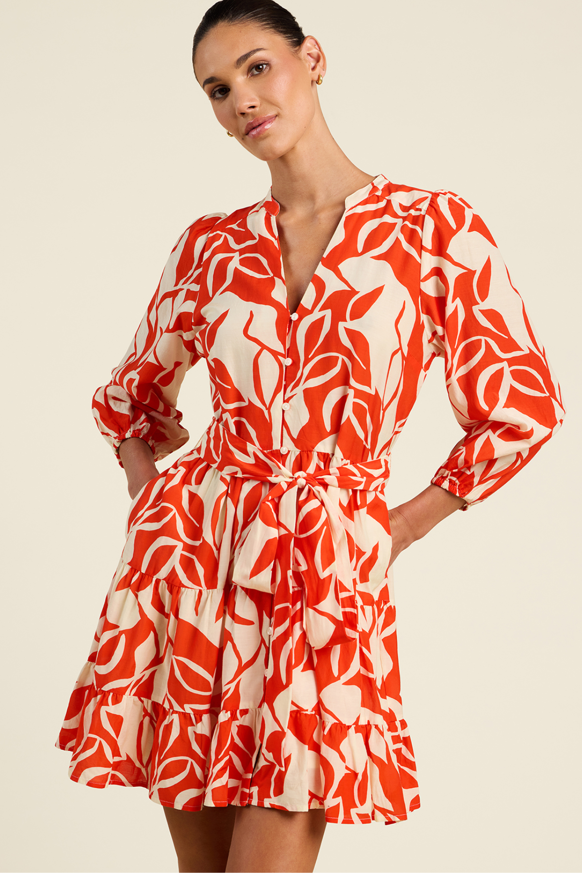 Woman wearing a red and white patterned dress on a beige background