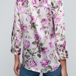 Model wearing rose print blouse with jeans on white background.