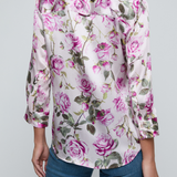 Model wearing rose print blouse with jeans on white background.
