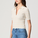 Model wearing a white printed blouse with colorful accents and short sleeves.