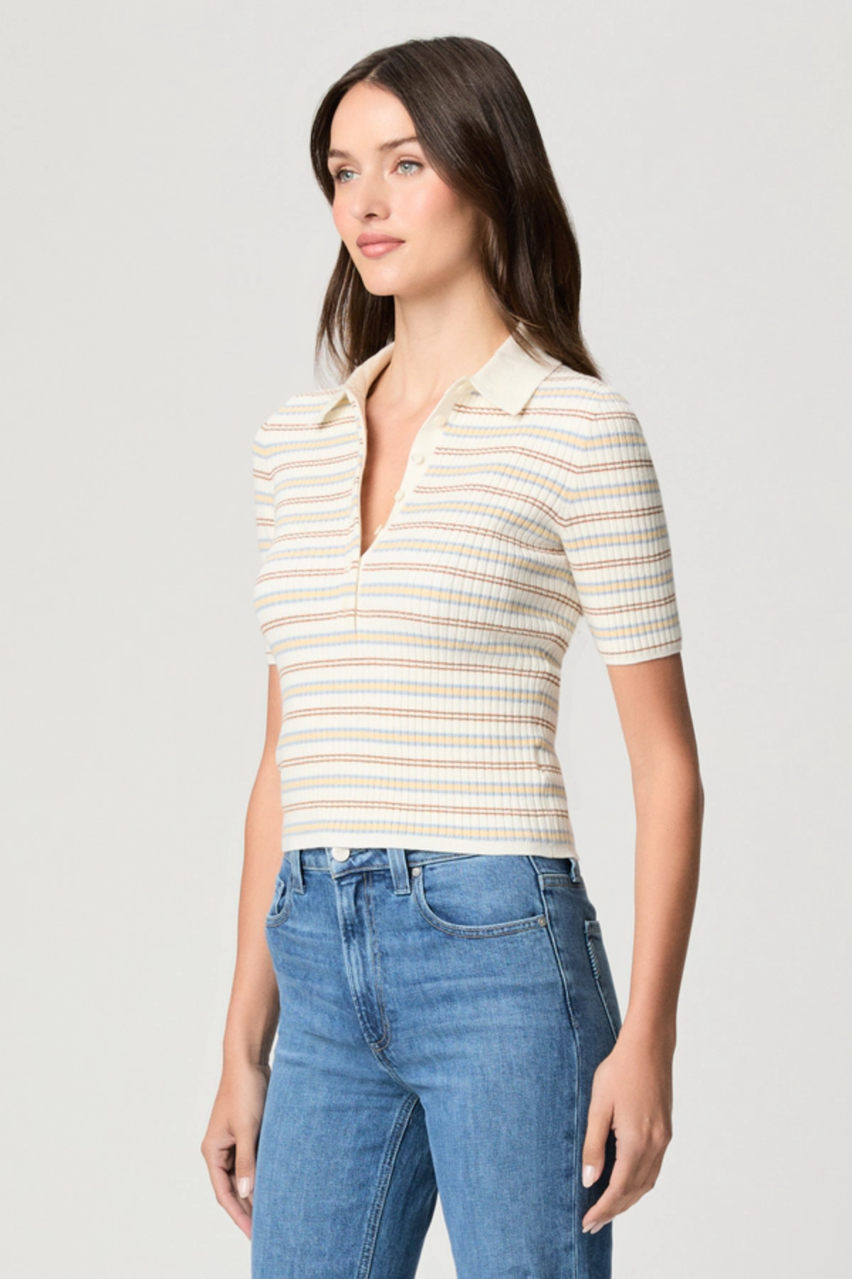 Model wearing a white printed blouse with colorful accents and short sleeves.