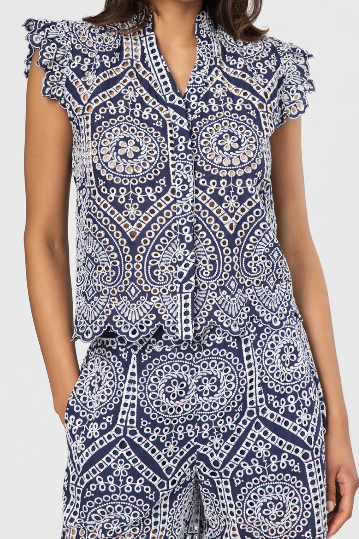 Navy and white patterned top with ruffled sleeves on a plain background