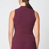 A woman shown from the back wearing a sleeveless ribbed knit top and matching pleated skirt in a deep plum purple color, set against a plain light gray studio background.