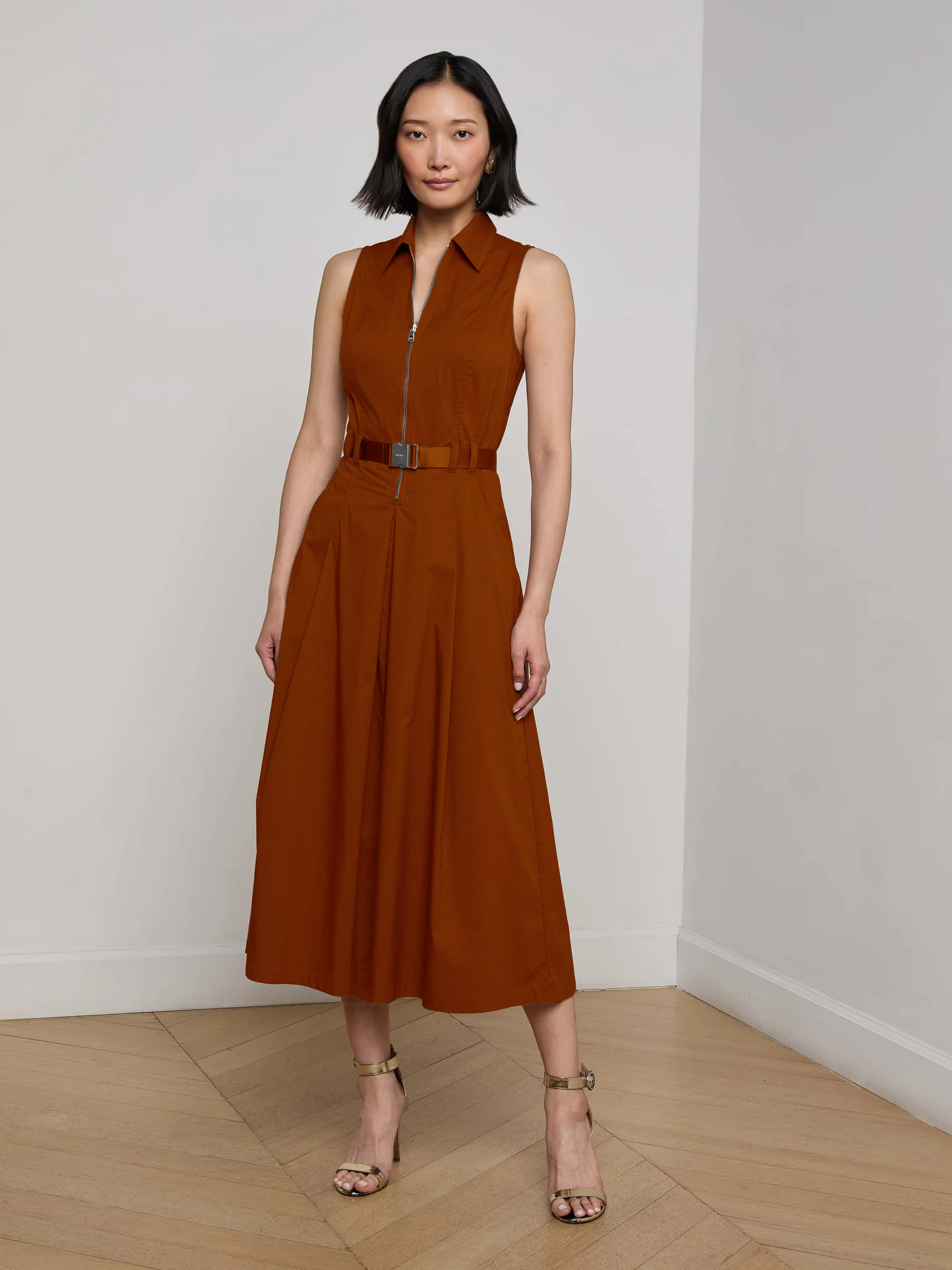 Model wearing a burnt orange midi dress with a white background. 