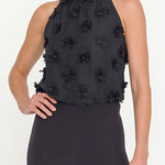 Black sleeveless top with floral embellishments worn by a model on a white background
