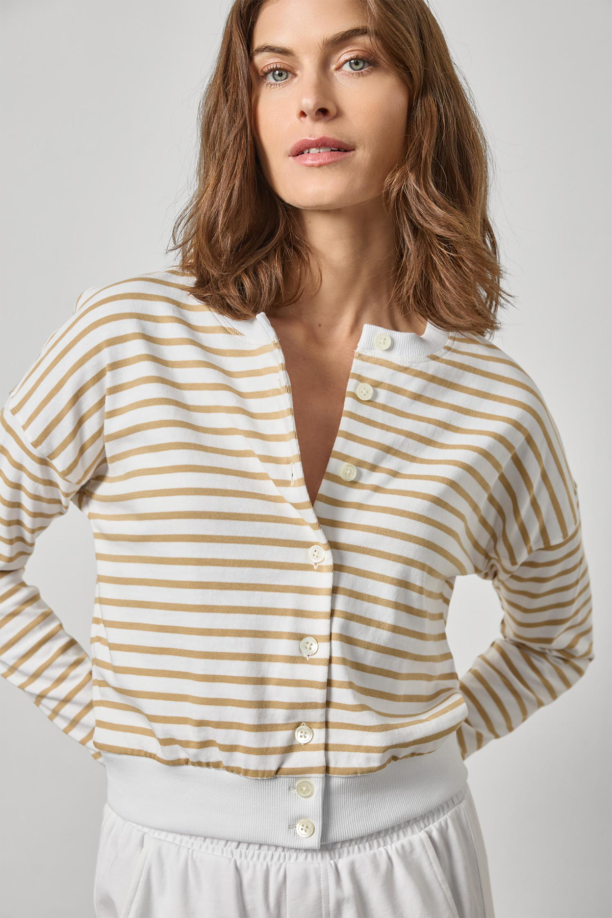 Woman wearing a yellow and white striped shirt against a plain background