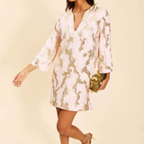 Woman wearing a floral dress with gold accents against a beige background