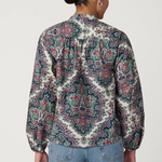 Person wearing a patterned shirt and jeans on a plain background