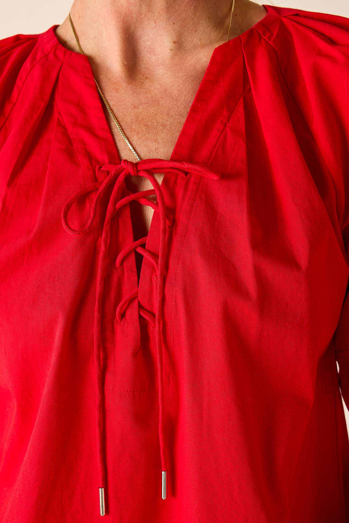 Red blouse with a tie neckline on a plain background