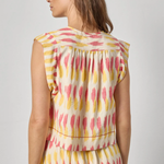 Woman wearing a sleeveless dress with a colorful abstract pattern on a plain background