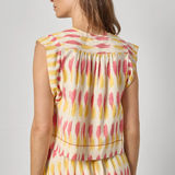 Woman wearing a sleeveless dress with a colorful abstract pattern on a plain background