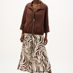 Woman wearing a brown jacket and zebra print skirt on a white background