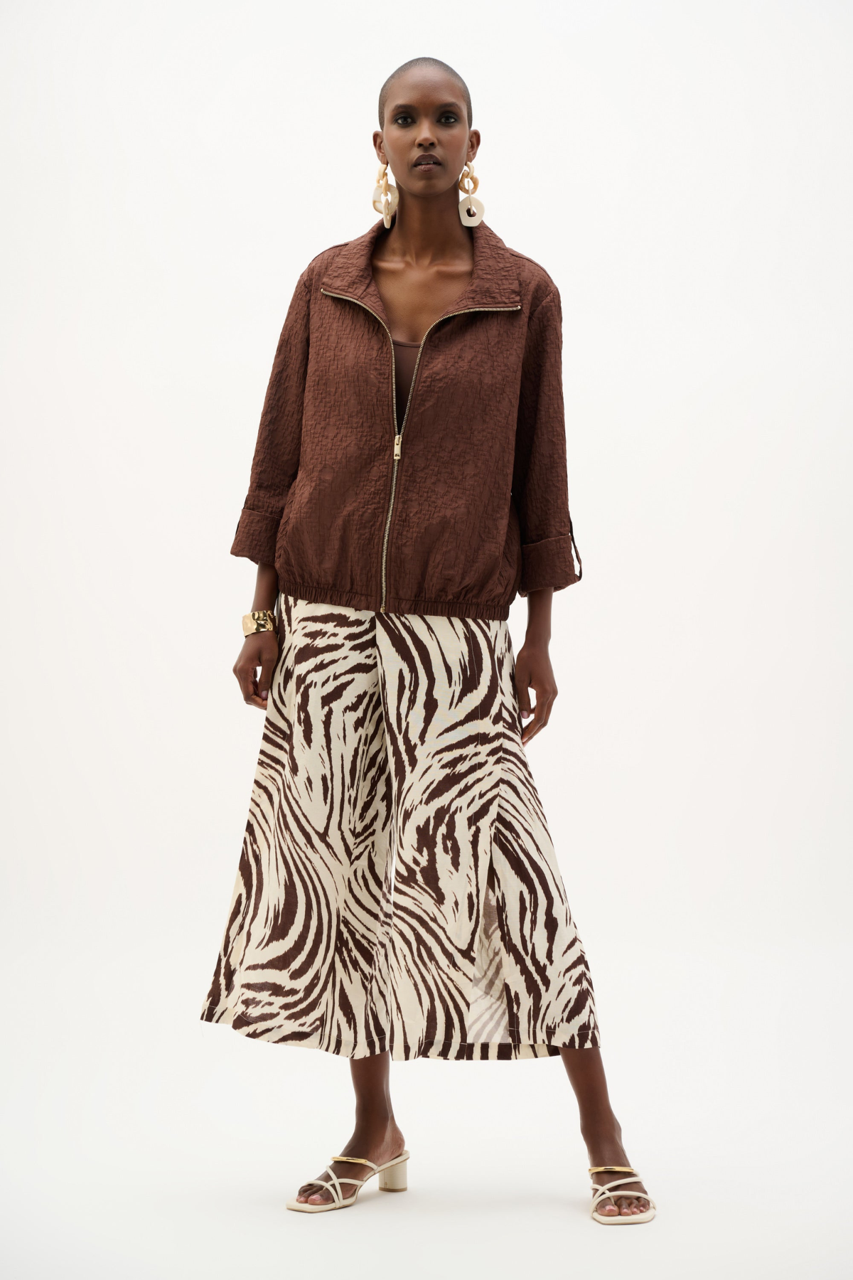 Woman wearing a brown jacket and zebra print skirt on a white background