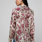 Woman wearing a floral blouse with red flowers on a plain background