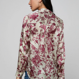 Woman wearing a floral blouse with red flowers on a plain background