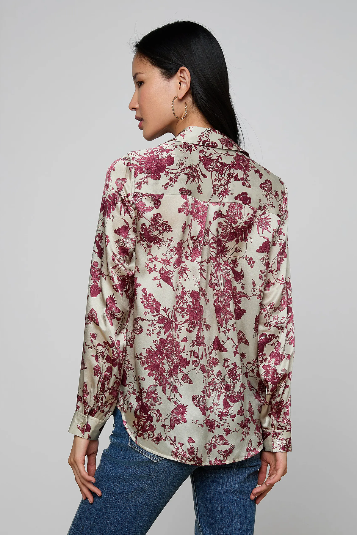 Woman wearing a floral blouse with red flowers on a plain background