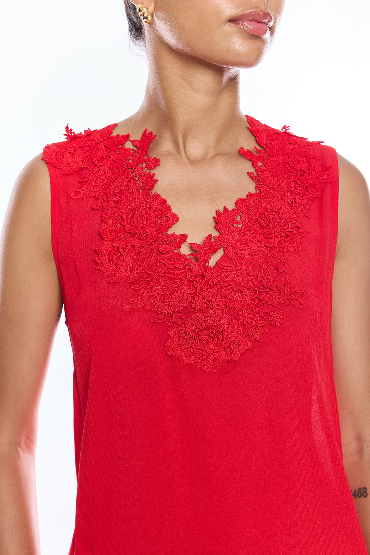 Red sleeveless top with floral lace details on a white background