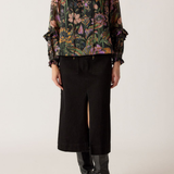 Person wearing a floral blouse and black skirt with black boots on a white background