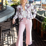 Woman in floral jacket and pink pants standing in an outdoor cafe setting