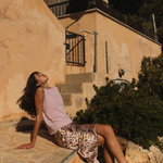 Woman sitting on stone steps in front of a building with a satellite dish.