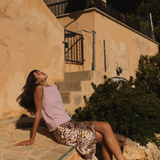 Woman sitting on stone steps in front of a building with a satellite dish.
