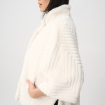 Woman wearing a white fur shrug against a plain background