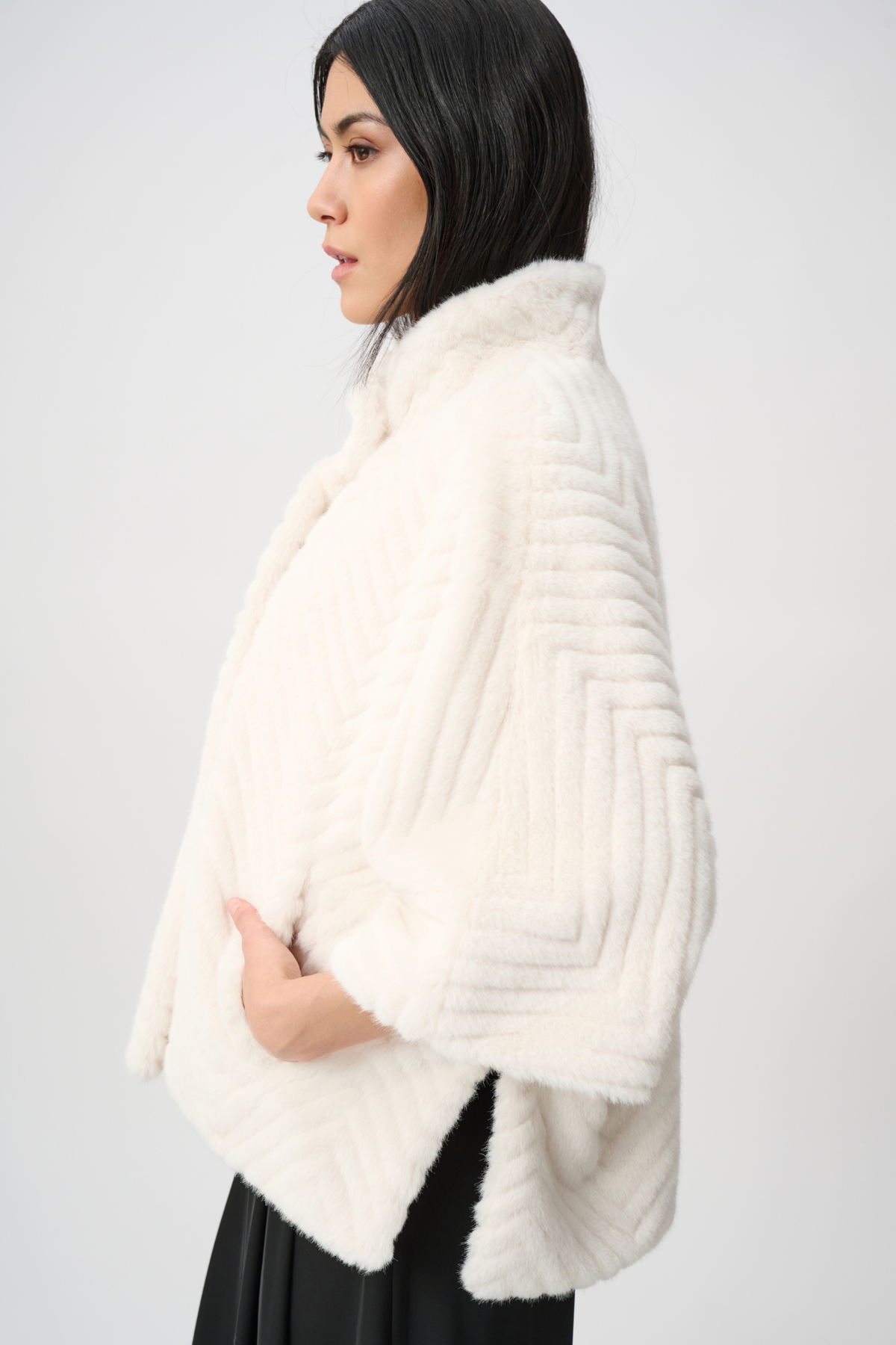 Woman wearing a white fur shrug against a plain background