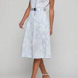Woman wearing a light blue sleeveless dress with a belt on a gray background