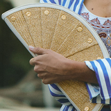 Person holding a woven clutch with a blurred background