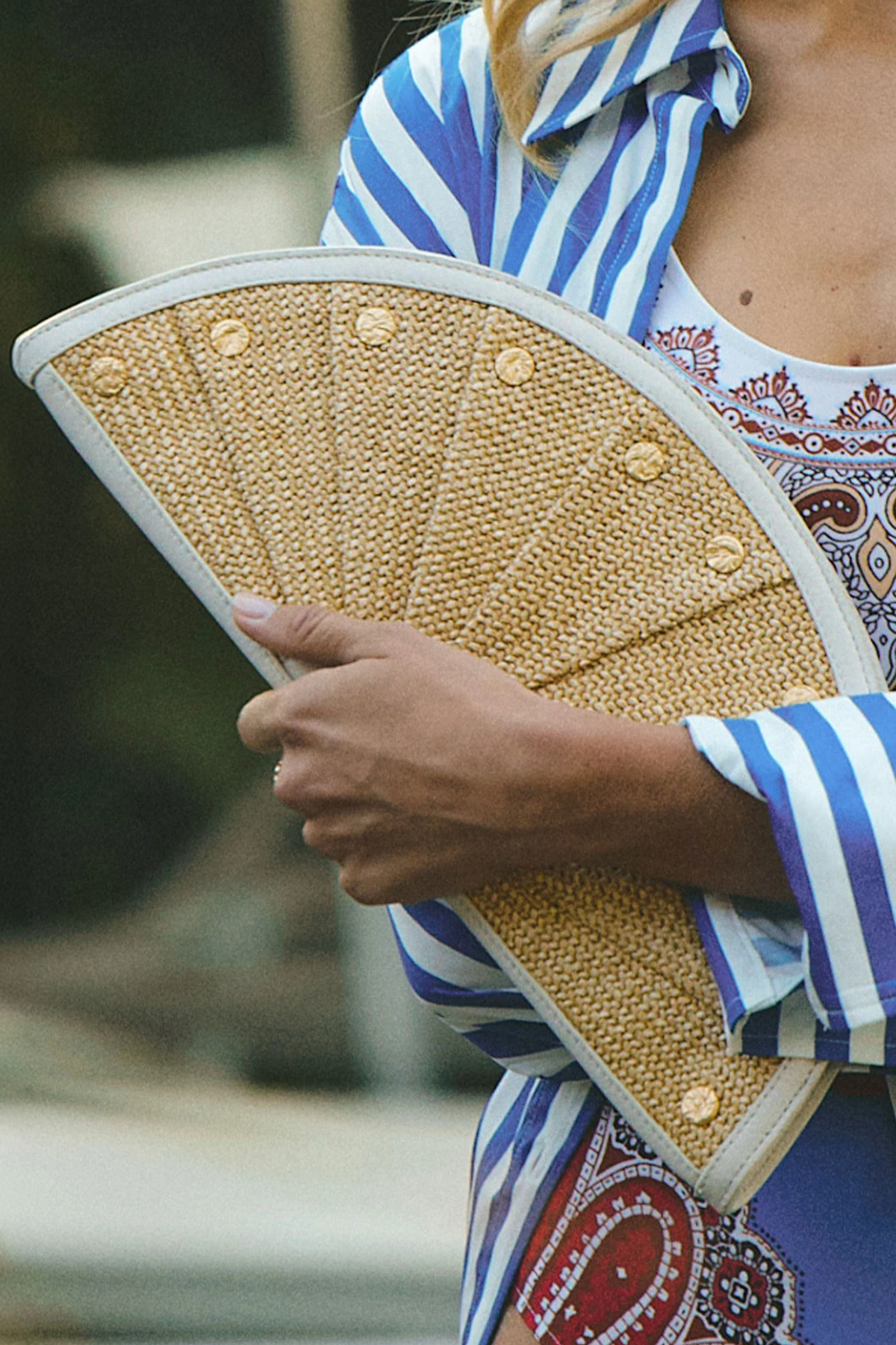 Person holding a woven clutch with a blurred background