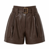 A pair of high-waisted brown faux-leather shorts with pleated side details, a matching belt, and a gold-tone buckle, shown on a plain white background.