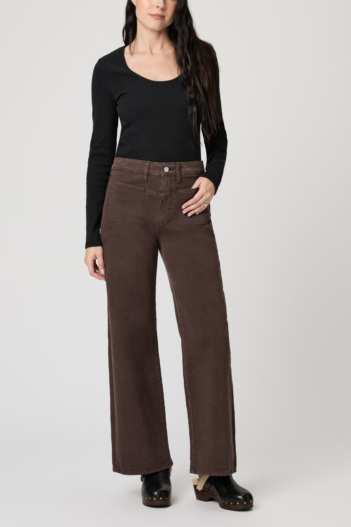 Person wearing brown wide-leg pants and a black top on a white background