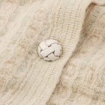 Close-up of a textured beige fabric with braided buttons.