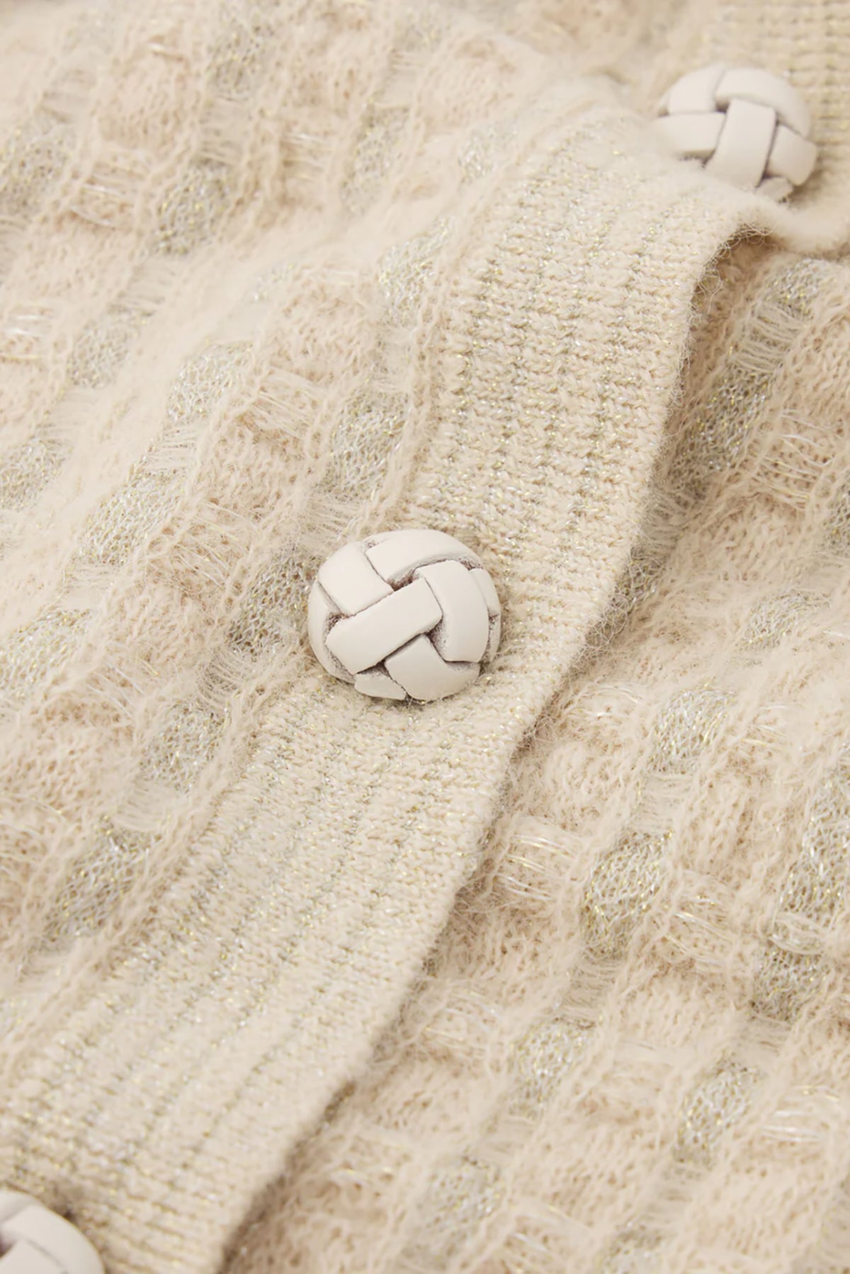 Close-up of a textured beige fabric with braided buttons.