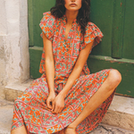 Woman in a floral dress sitting on stone steps with a green door in the background
