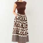 Woman wearing a brown top and patterned skirt on a white background