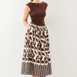 Woman wearing a brown top and patterned skirt on a white background
