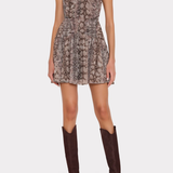 A sleeveless mini dress with a snakeskin pattern in brown, beige, and gray tones, worn by a model with dark brown knee-high boots against a light gray background.
