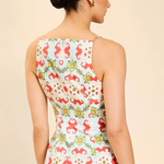 Woman wearing a sleeveless top with a colorful floral pattern on a beige background