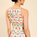 Woman wearing a sleeveless top with a colorful floral pattern on a beige background